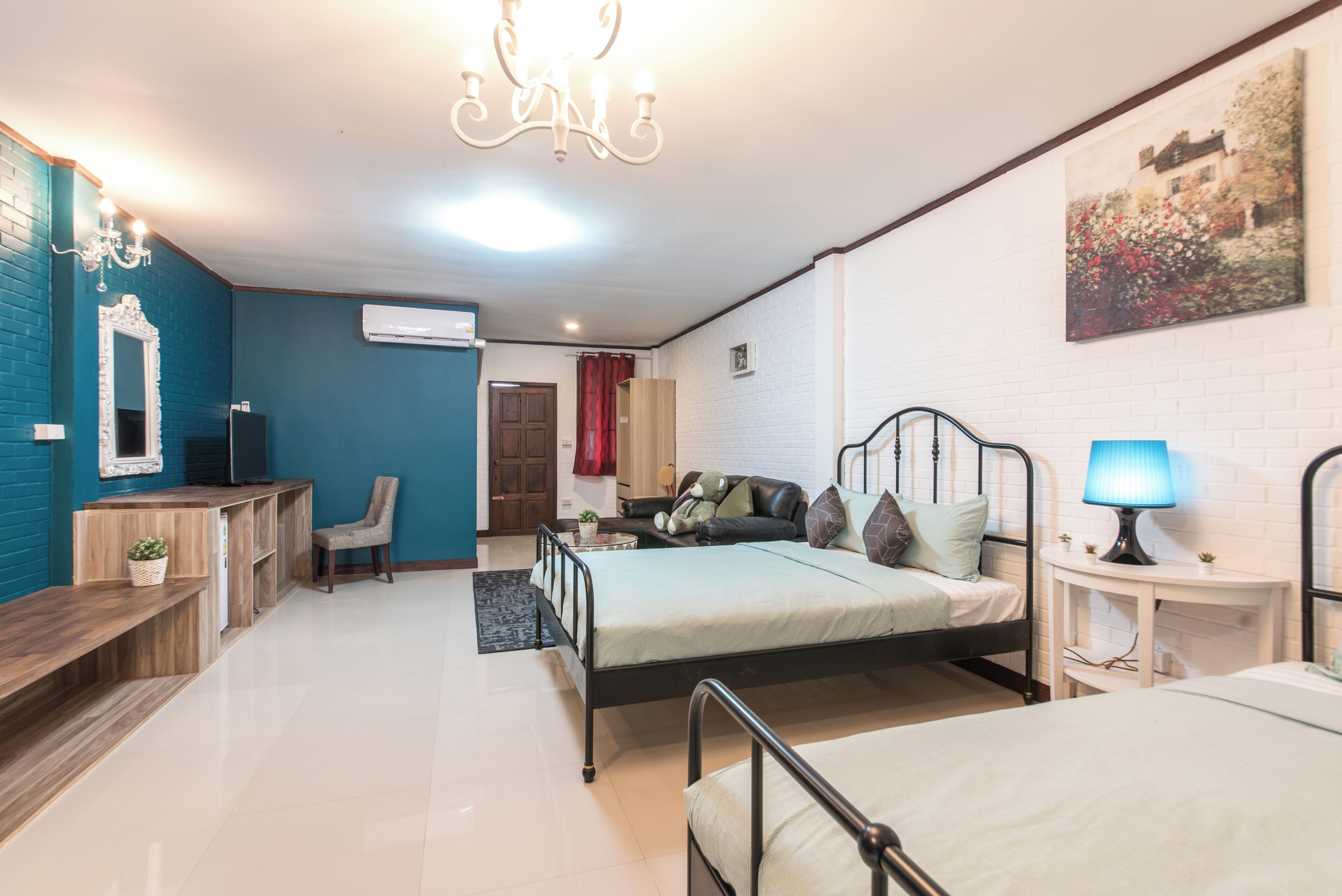 A room with a bed, bedside table, lamp, chair, desk, and a TV.