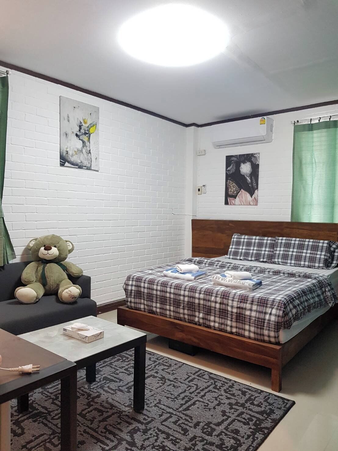 A bedroom with a bed, a chair, a table, and a teddy bear.