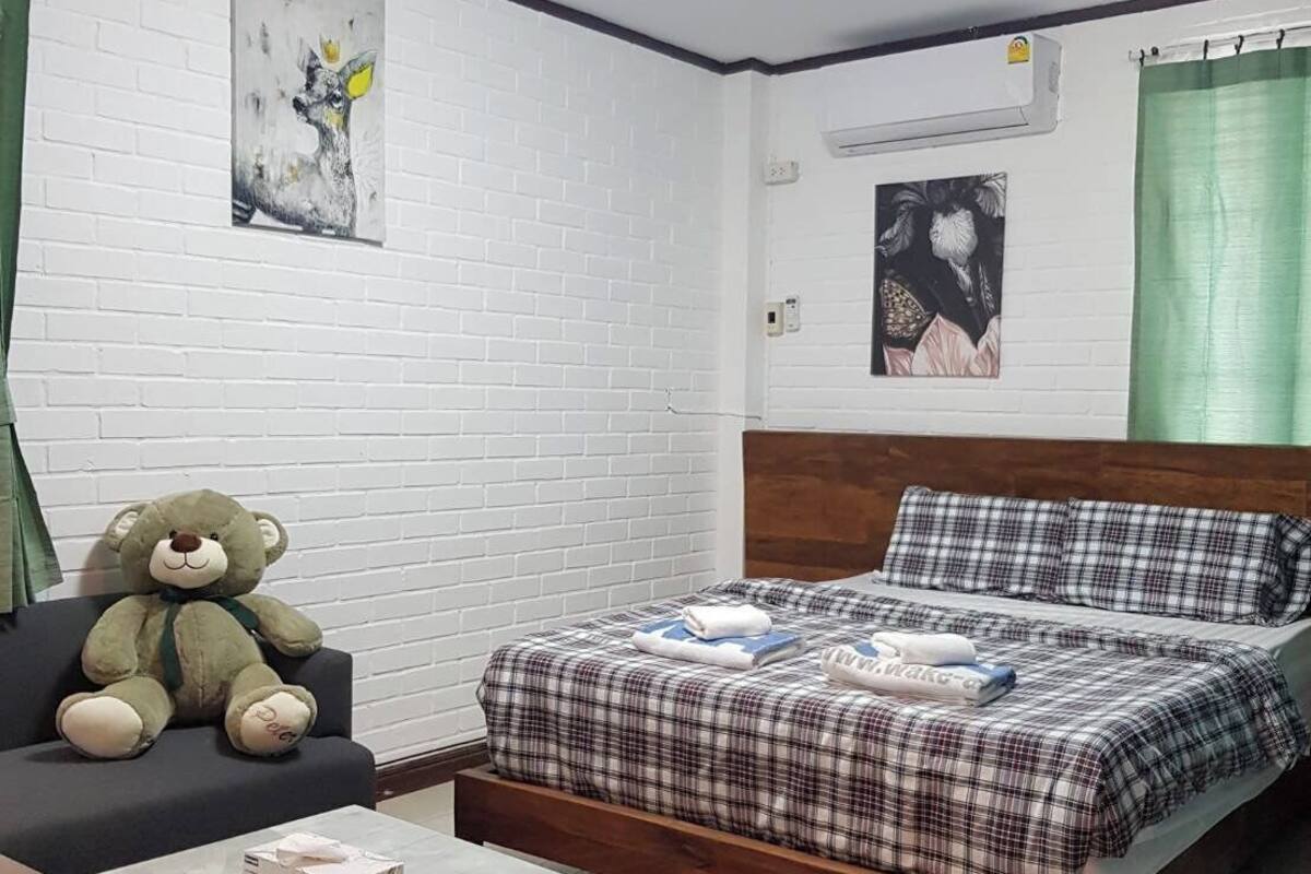 Une chambre à coucher avec un lit, une chaise, une table et un ours en peluche.