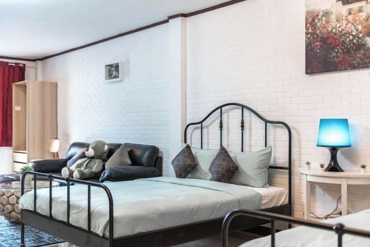 A single bed with a metal frame, a bedside table with a lamp, and a wall-mounted picture.