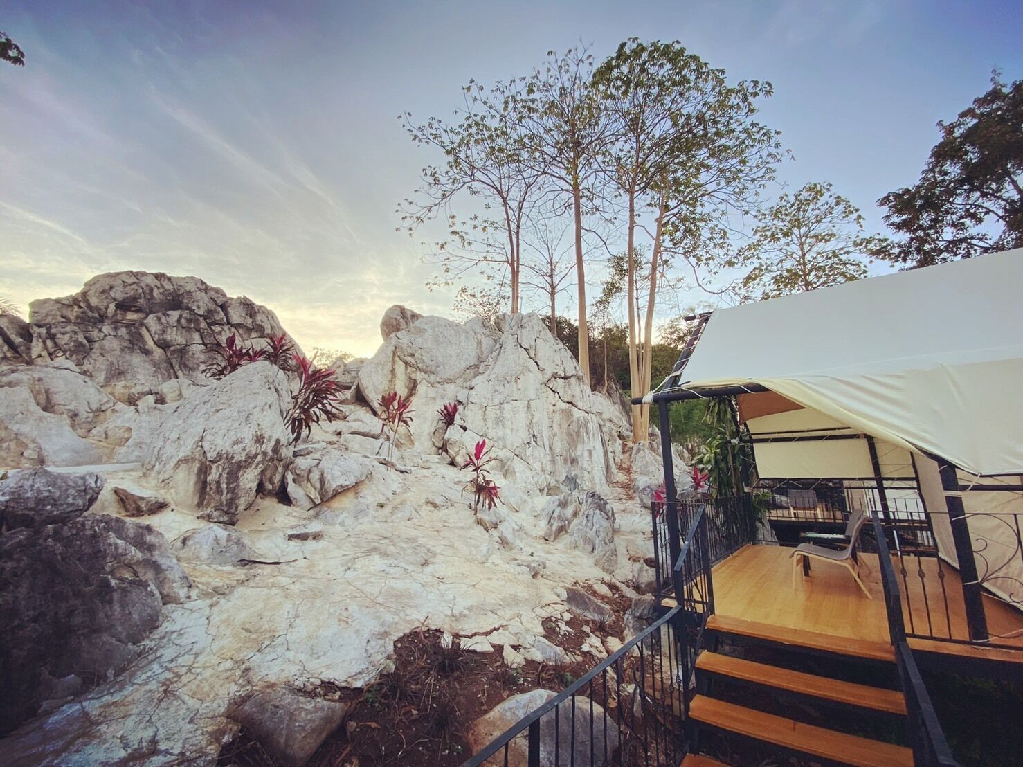 A rocky landscape with a white tent and a wooden staircase leading up to it.