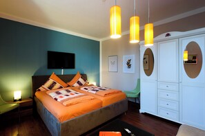 A bedroom with a bed, bedside table, lamp, TV, wardrobe, and a chair.