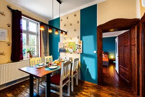 A dining area with a wooden table, chairs, and a window with curtains.