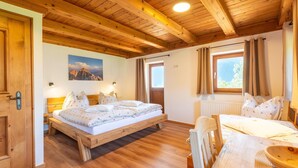 A wooden-framed bedroom with a bed, a table, and a window with curtains.