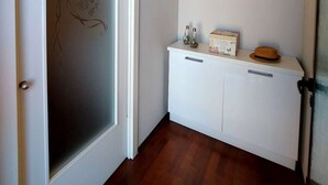 Ein Flur mit einer Tür aus Milchglas, einem weißen Konsolentisch mit Dekoration und einer Wand mit einem Motivationsspruch.