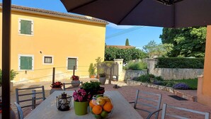 Eine Terrasse im Freien mit Esstisch, umgeben von Blumentöpfen und einer Steinmauer.