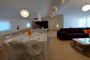 A modern living space with a dining area, a dark-colored sofa, and a kitchen in the background. - New flat with whirlpool for 6 people (Rovinjsko Selo)