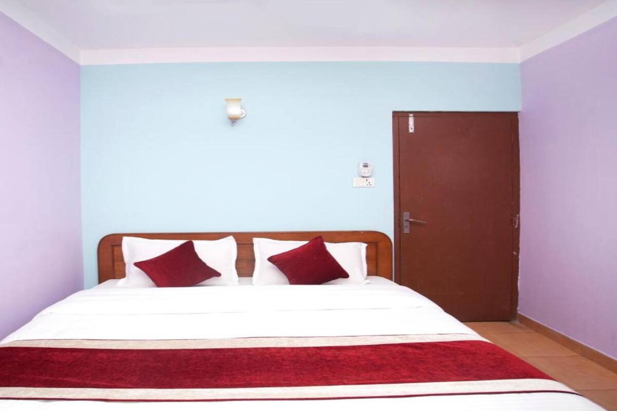 A bedroom with a bed, a door, and a wall-mounted light fixture.