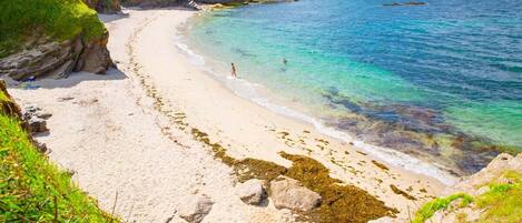 Una playa con agua turquesa cristalina y un litoral rocoso.
