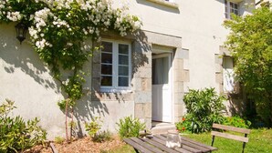 A house with a garden, a wooden bench, and a white door. - Apartment 'Prat Bras - T1 Cocooning' with Shared Garden and Wi-Fi (Clohars-Carnoët)