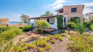 Ein Küstenhaus mit Terrasse, Meerblick und Garten mit verschiedenen Pflanzen.