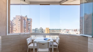 A balcony with a table and chairs, a book on the table, and a cityscape view.