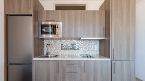 A modern kitchen with a stainless steel refrigerator, microwave, and double sink.