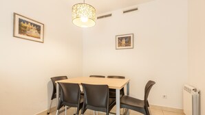 Ein Essbereich mit Tisch und Stühlen, einer Hängeleuchte und zwei gerahmten Bildern an der Wand.