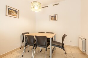 Un comedor con una mesa y sillas, una lámpara colgante y dos cuadros en la pared.