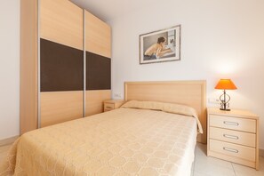 Un dormitorio con una cama, una mesita de noche, una lámpara y un cuadro en la pared.