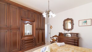 Habitación de hotel con una cama grande, armario de madera, un espejo y una araña.