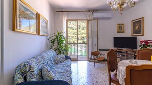 Una sala de estar con sofá, mesa de comedor, sillas, televisor y candelabro.