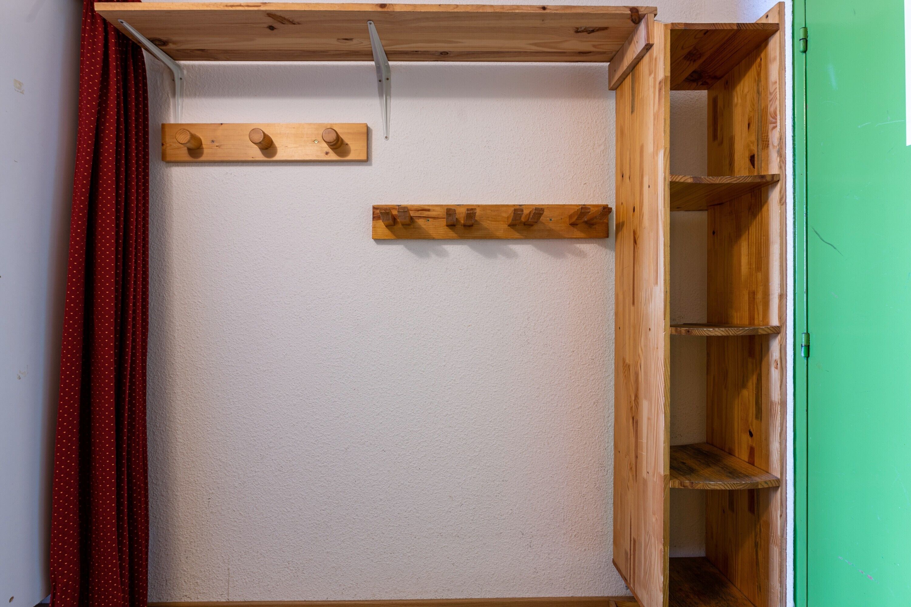 Ein Zimmer mit einer Holzeinrichtungsanlage, einem roten Vorhang und einer grünen Tür.