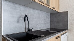 A kitchen with a black sink, wooden cabinets, and a dishwasher.