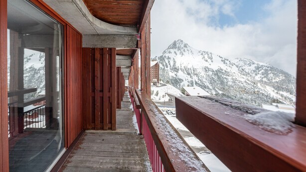 A wooden balcony with a view of snow-covered mountains.