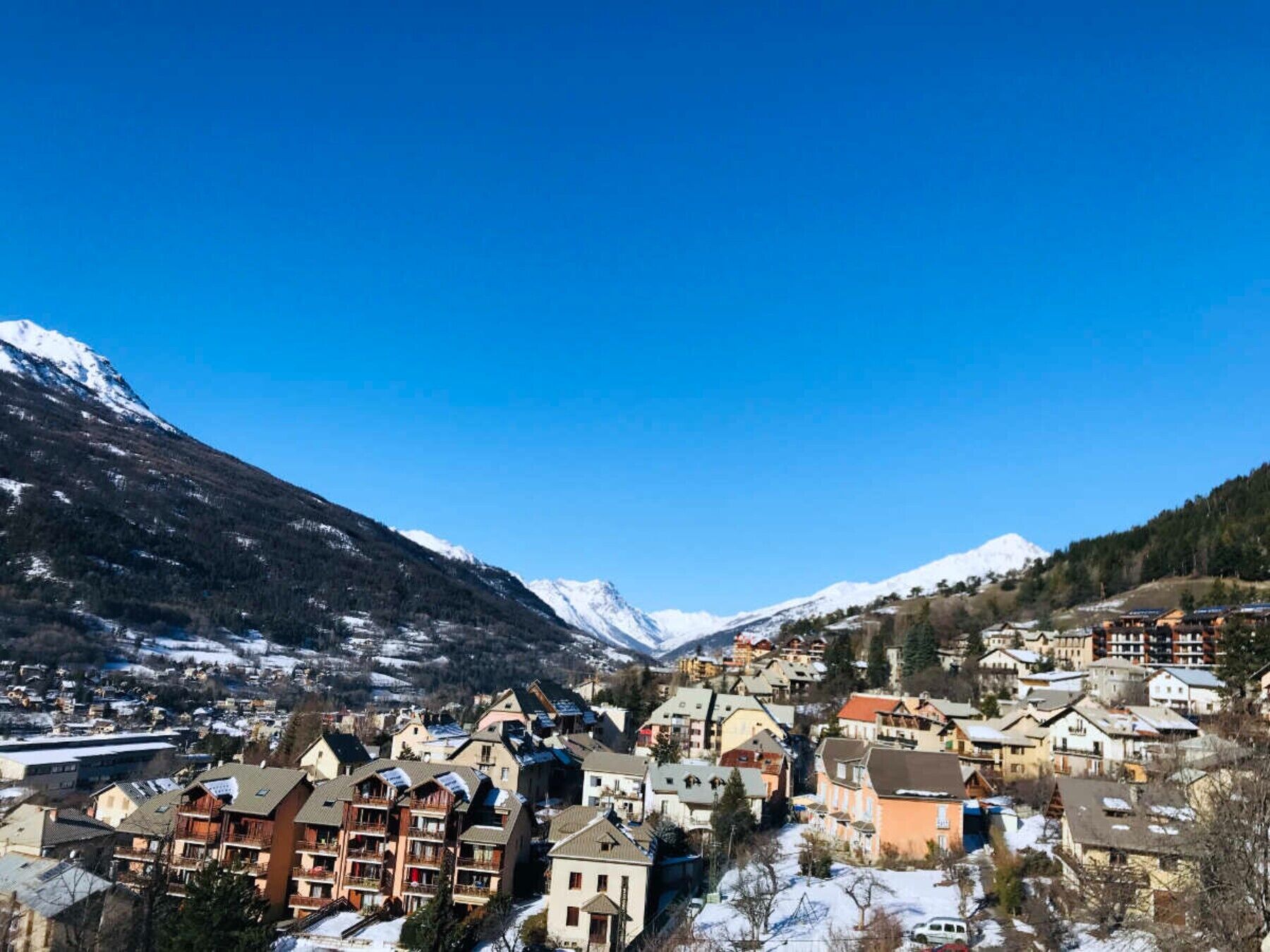 Une ville de montagne aux bâtiments enneigés, avec des montagnes en toile de fond.