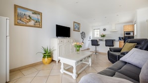 A living room with a sofa, a TV, a white table, and a potted plant. - Holiday Home 'Maison Piscine Chauffe Jacuzzi' with Private Terrace, Private Garden and Wi-Fi (Tourrettes)