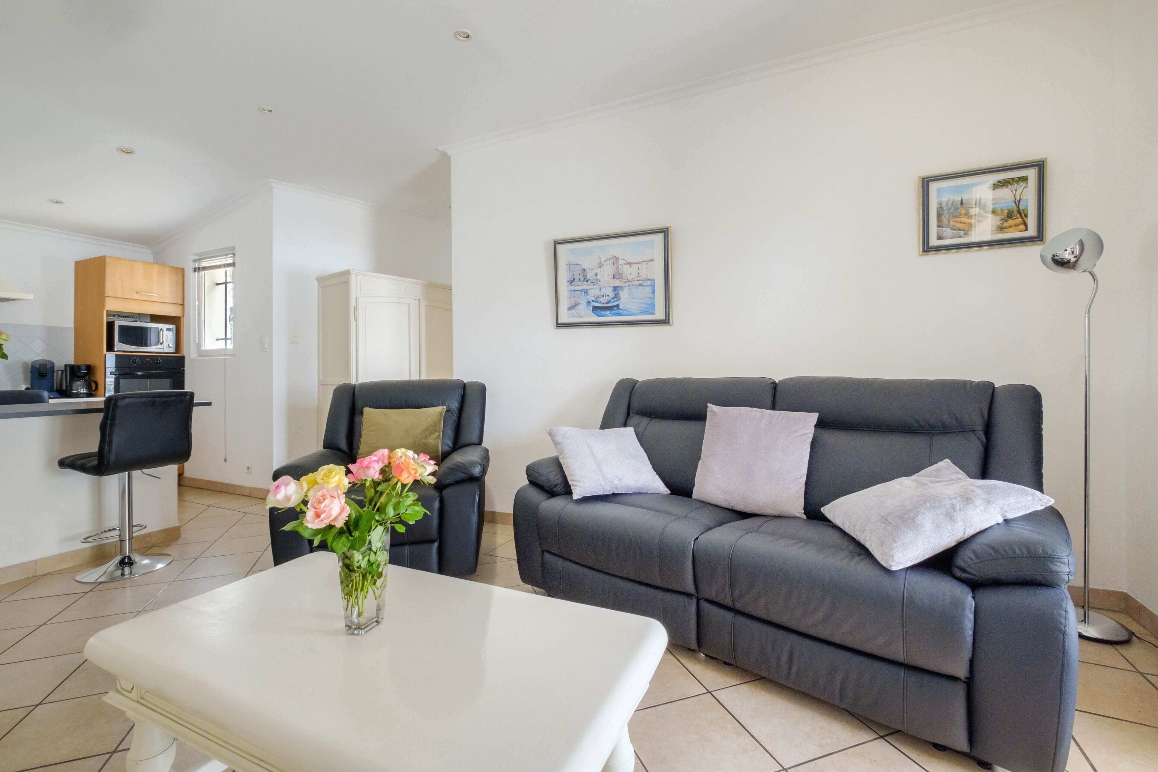A modern living room with a grey sofa, a white coffee table, and a vase of flowers.
