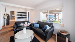 A modern living room with a black leather sofa, a white coffee table, and a view of the outdoor patio. - Holiday Home 'Casa Blanca Family Villa' with Private Pool, Wi-Fi & Air Conditioning (alfaz del pi)
