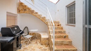 A stone staircase leading to a second floor, a barbecue grill, and a small table with chairs. - Holiday Home 'Casa Blanca Family Villa' with Private Pool, Wi-Fi & Air Conditioning (alfaz del pi)