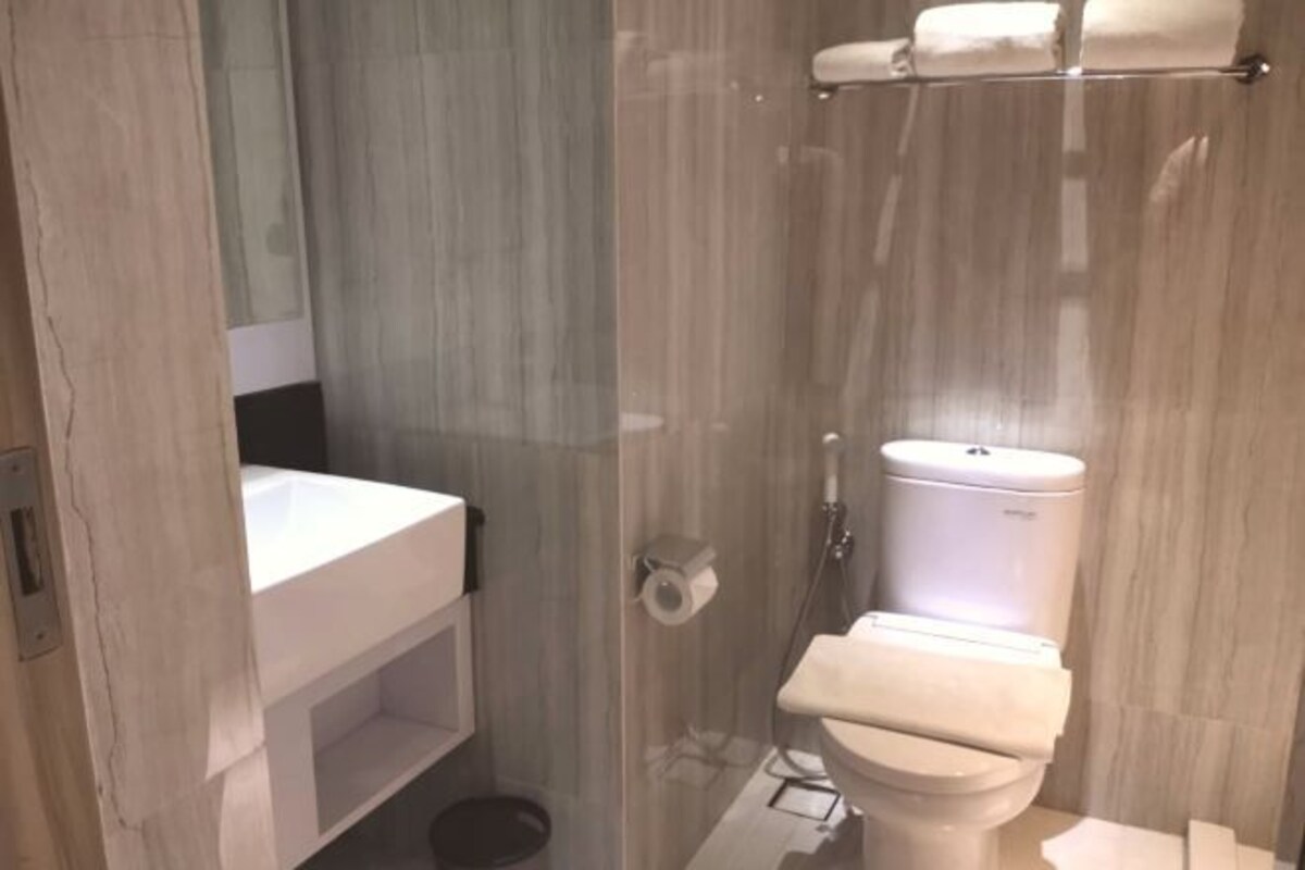 Un baño moderno con cabina de ducha de vidrio, inodoro blanco y lavabo con espejo.