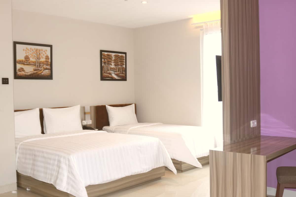 A hotel room with two beds, a desk, and a chair.