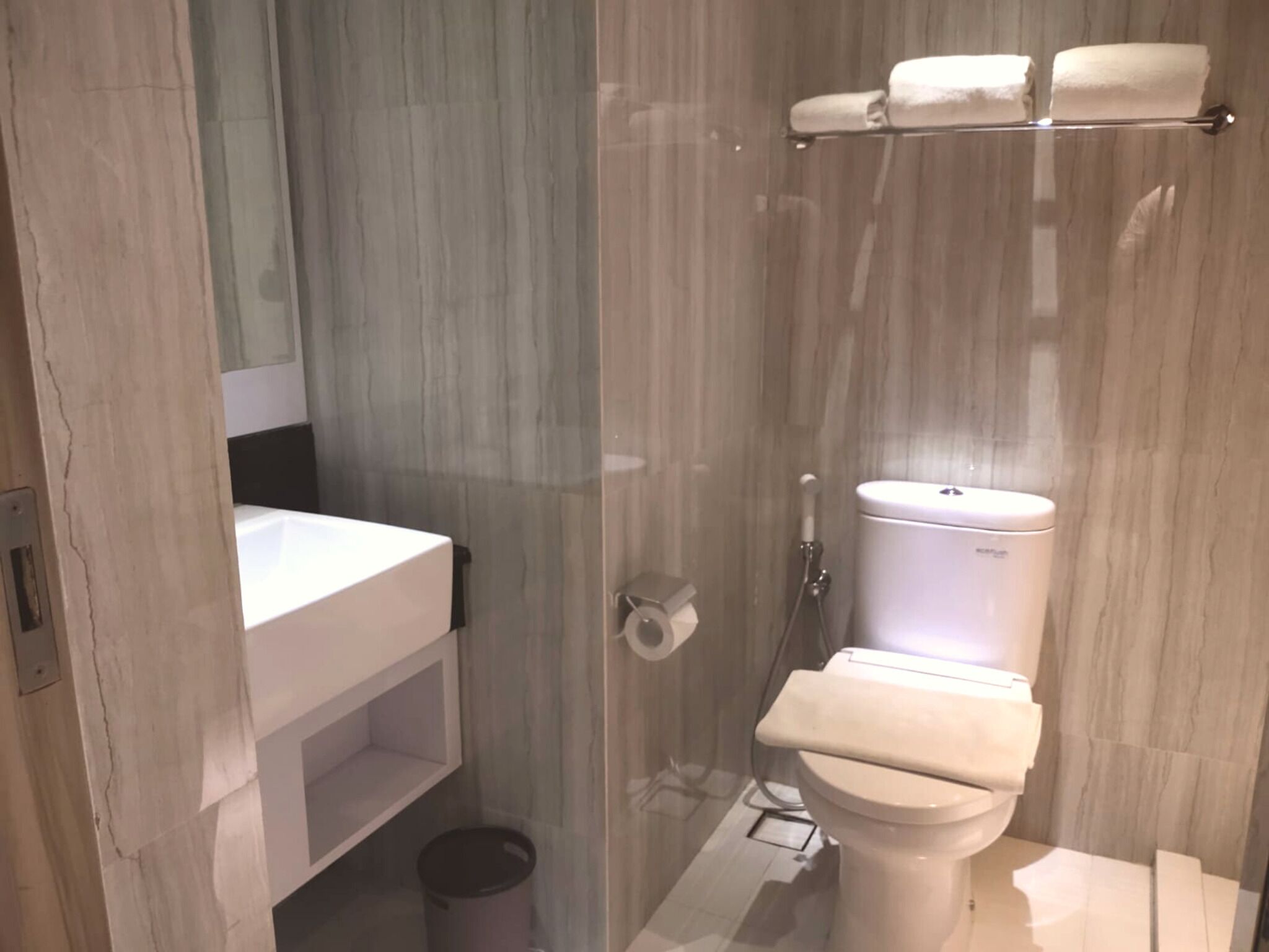 A modern bathroom with a glass shower enclosure, a white toilet, and a sink with a mirror above it.