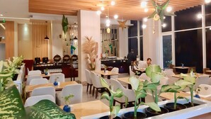 A modern restaurant interior with wooden ceiling panels, hanging lights, and potted plants on tables. - Surabaya River View Hotel (Surabaya)