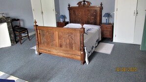 Un dormitorio con cama de madera, una silla, una mesita de noche y un armario.