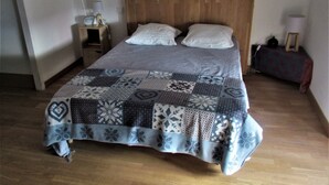 Una cama bien tendida con colcha estampada, un cabecero de madera y una mesita de noche con una lámpara.