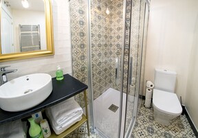 A bathroom with a white sink, black countertop, and a glass-enclosed shower.