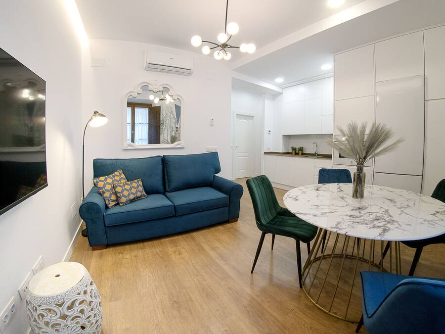 A modern living room with a blue sofa, a round dining table, and a green chair.