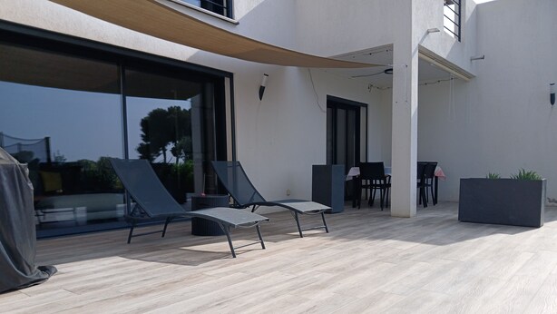 An outdoor patio with two lounge chairs, a table, and a planter.