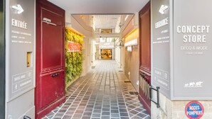 A hotel corridor with red doors, a tiled floor, and directional signs for 'ENTRÉE' and 'ENTRANCE'. - Merveil - Luxury Suite - Tour Eiffel - Bac I (Paris)