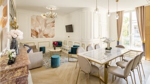 A dining area with a glass table, blue chairs, and a chandelier. - Merveil - Luxury Suite - Tour Eiffel - Bac I (Paris)