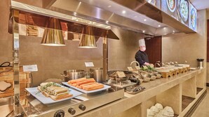 A buffet setup with various food items and a chef preparing food. - Shenzhen Guangming CIMC Executive Hotel (Shenzhen)