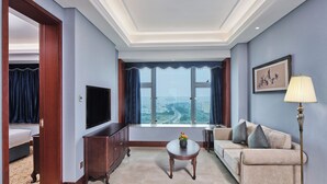 A hotel room with a large window, a sofa, a TV, a lamp, and a cabinet. - Shenzhen Guangming CIMC Executive Hotel (Shenzhen)