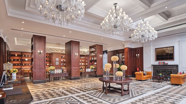 A spacious lobby with a checkered floor, large chandeliers, wooden bookshelves, and a fireplace. - Shenzhen Guangming CIMC Executive Hotel (Shenzhen)
