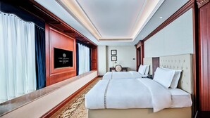 A hotel room with two beds, a large mirror, a desk, and a television displaying the hotel name. - Shenzhen Guangming CIMC Executive Hotel (Shenzhen)