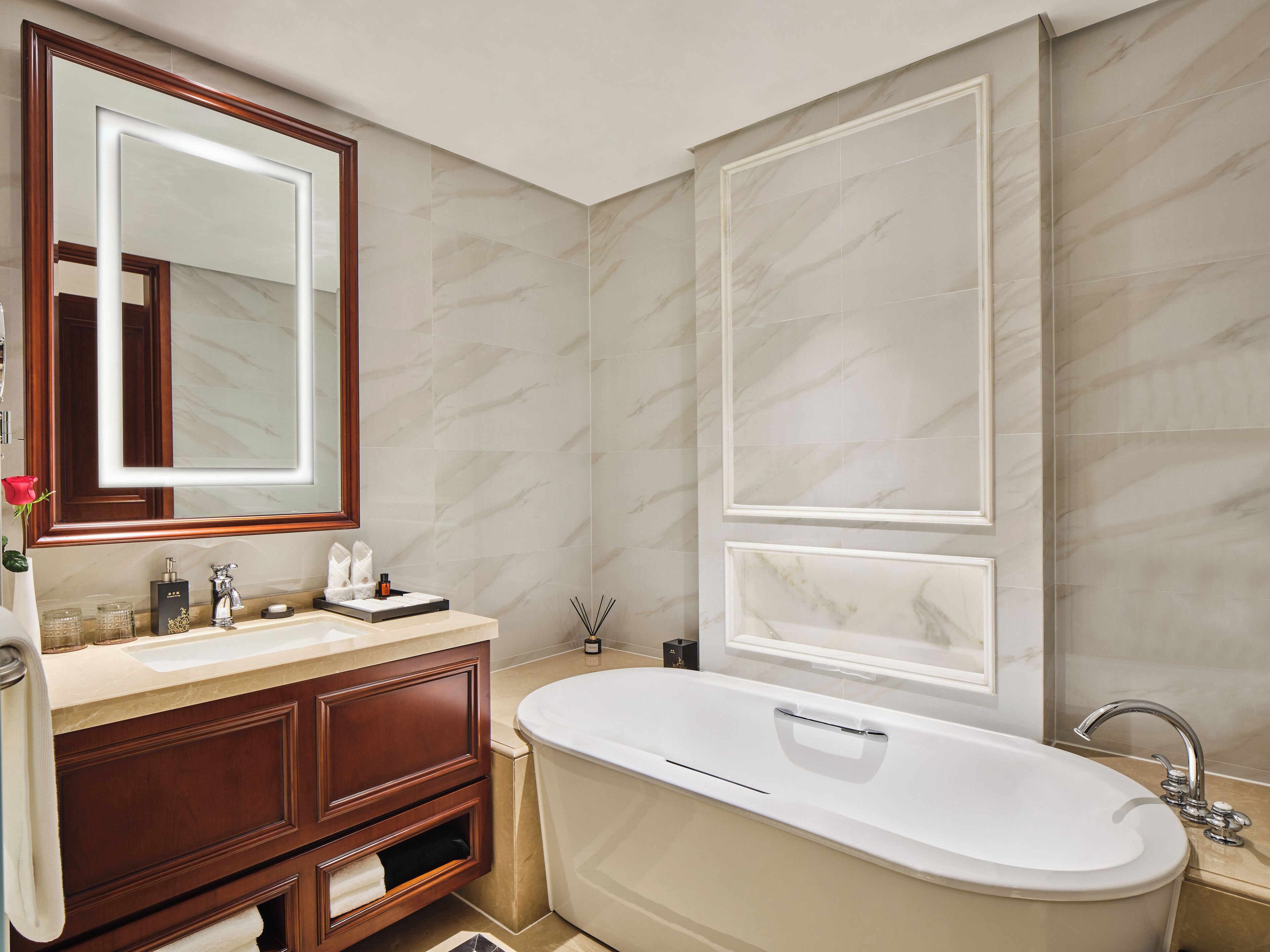 Een moderne badkamer met een vrijstaand bad, een grote spiegel en een wastafel met een marmeren blad.