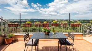 Une terrasse avec une table et des chaises, des plantes en pot et une vue sur le paysage.