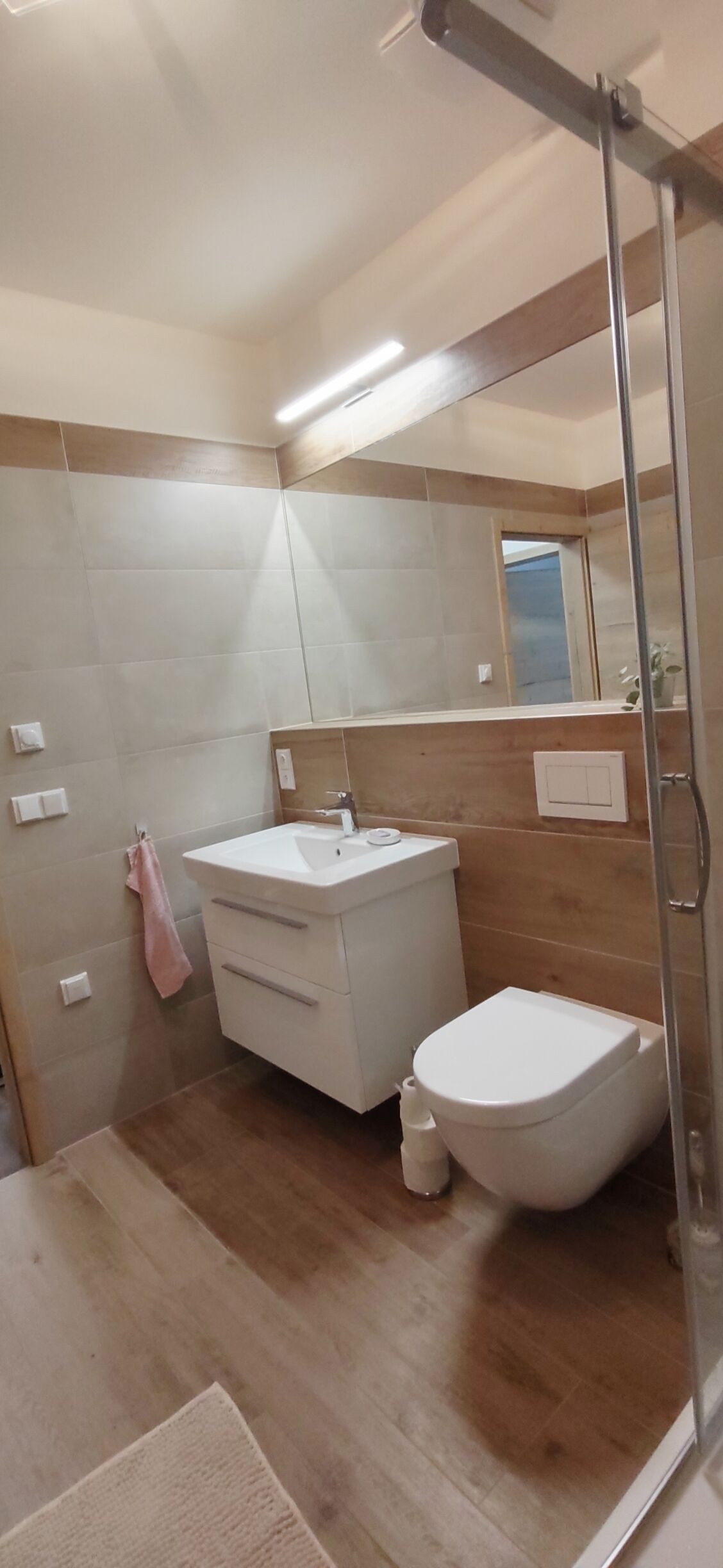 Un bagno moderno con lavandino bianco, un WC e una cabina doccia.