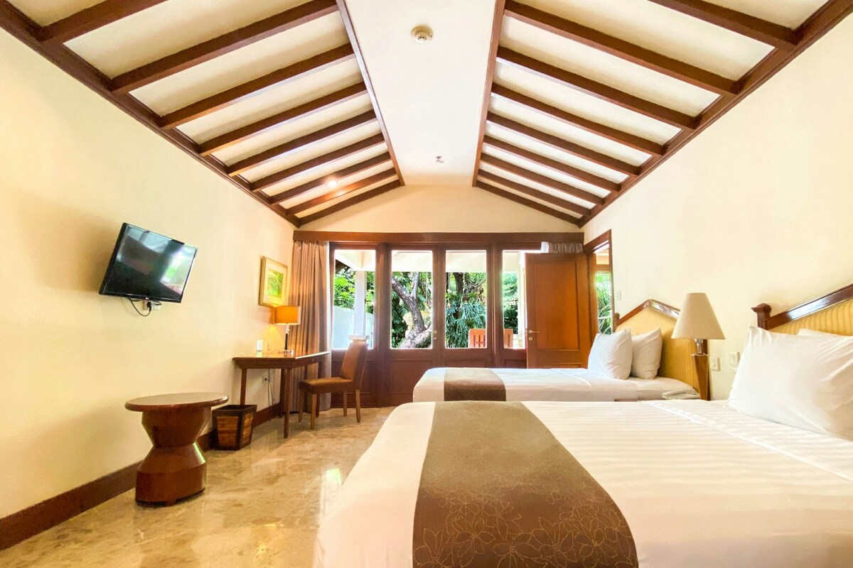 Habitación de hotel con cama, escritorio, silla, televisor y vistas al exterior.