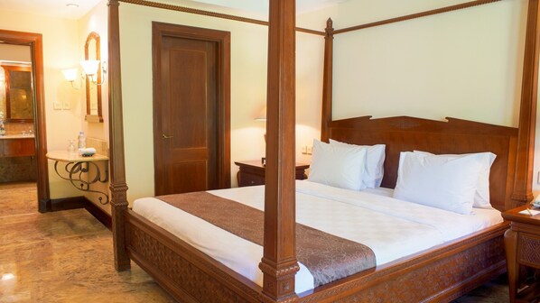 A four-poster bed with a wooden headboard, a bedside table, and a nightstand with a lamp.